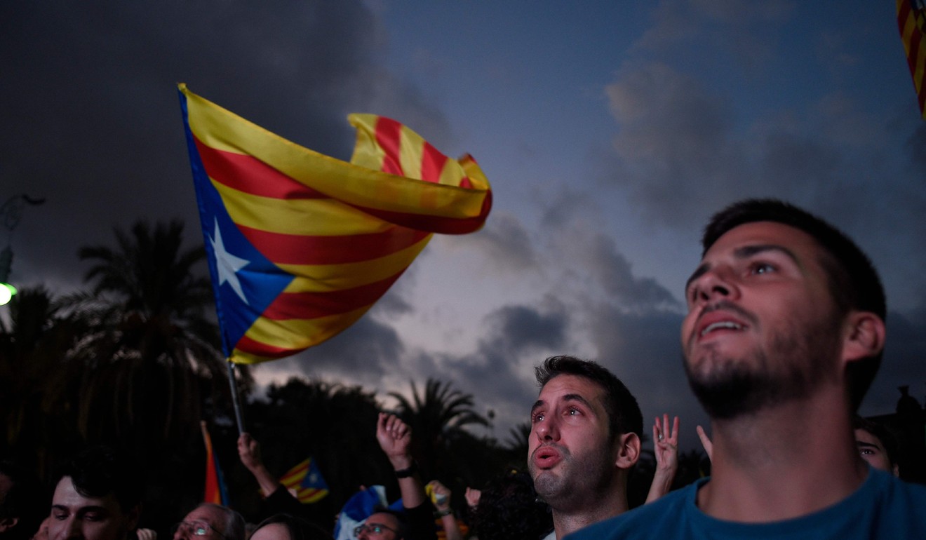 Supporters of independence for Catalonia listen to Catalan president Carles Puigdemont's speech broadcasted on a television screen at the Arc de Triomf in Barcelona last October. Photo: AFP
