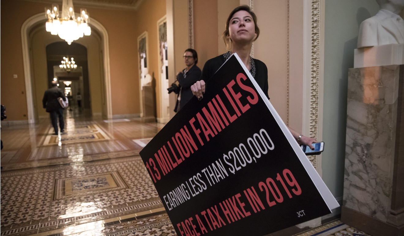 A staff member of one US Senator carries a poster criticising the Republican tax bill. Photo: AP