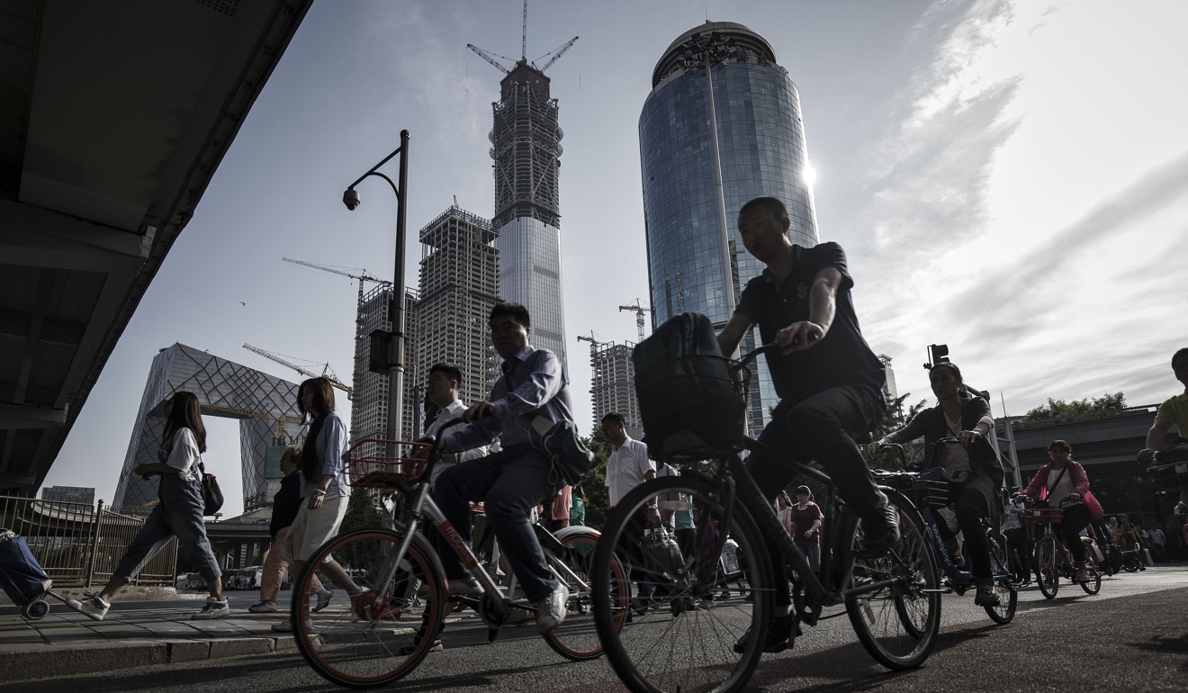 Cyclists pass pedestrians as they cycle along a road near the China Central Television (CCTV) headquarters building. Photo: Bloomberg