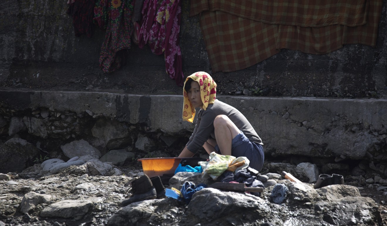 A North Korean woman washes clothes along the banks of North Korea across from the Chinese border town of Jian. Photo: AP