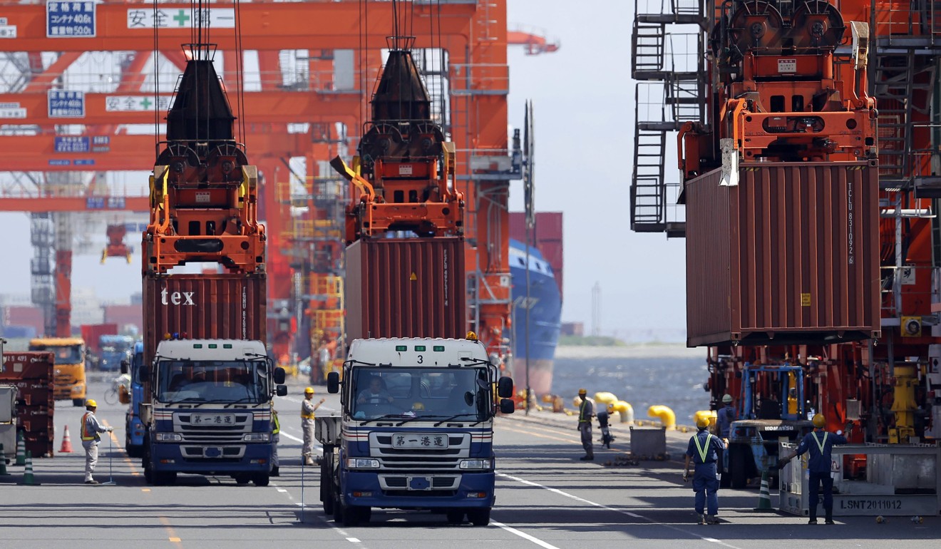 Workers load containers from trucks onto a cargo ship at a port in Tokyo. Photo: Reuters