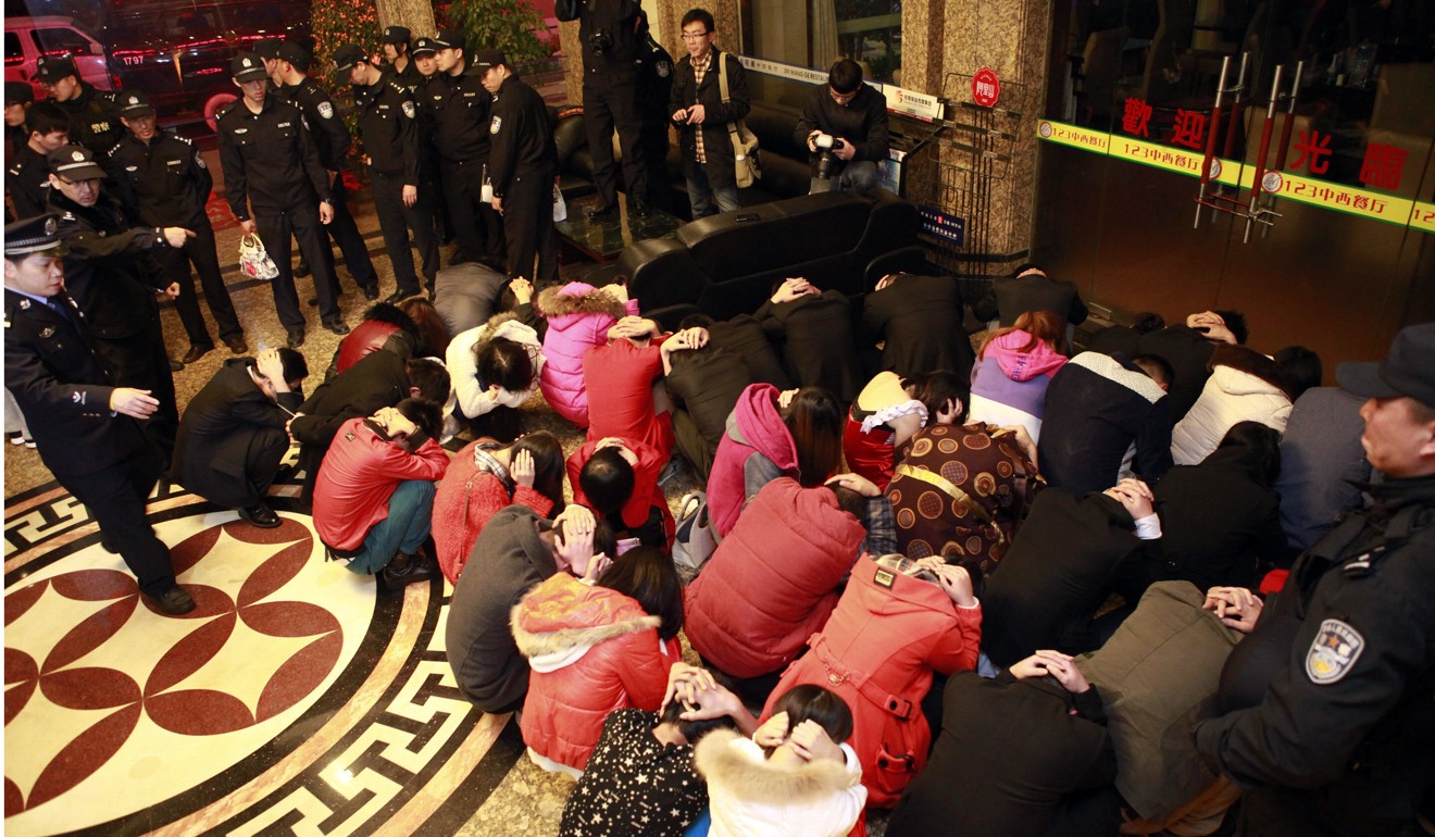 Police detain a group of suspects during an anti-prostitution raid at a hotel in Dongguan in February 2014. Photo: AP