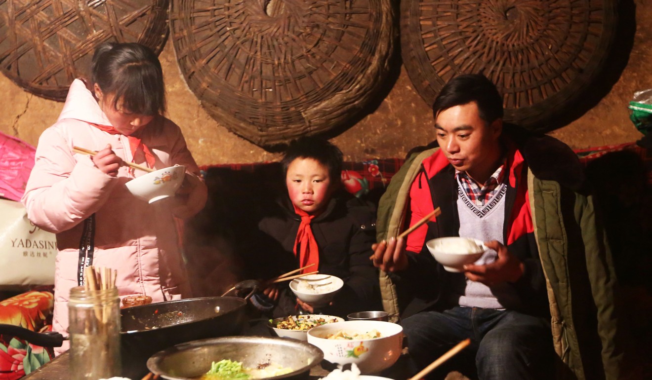 Wang Fuman (centre) eats with his family in Ludian, China, on January 11. A photo of the boy with his hair encrusted in ice after an hour-long walk to school went viral in January, stirring debate about the impact of poverty on children in rural regions. Photo: AFP
