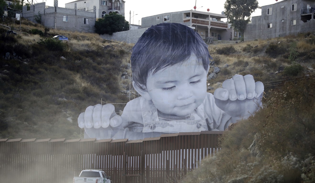 A US Border Patrol vehicle drives in front of a mural in Tecate, Mexico, just beyond a border wall structure. Photo: AP