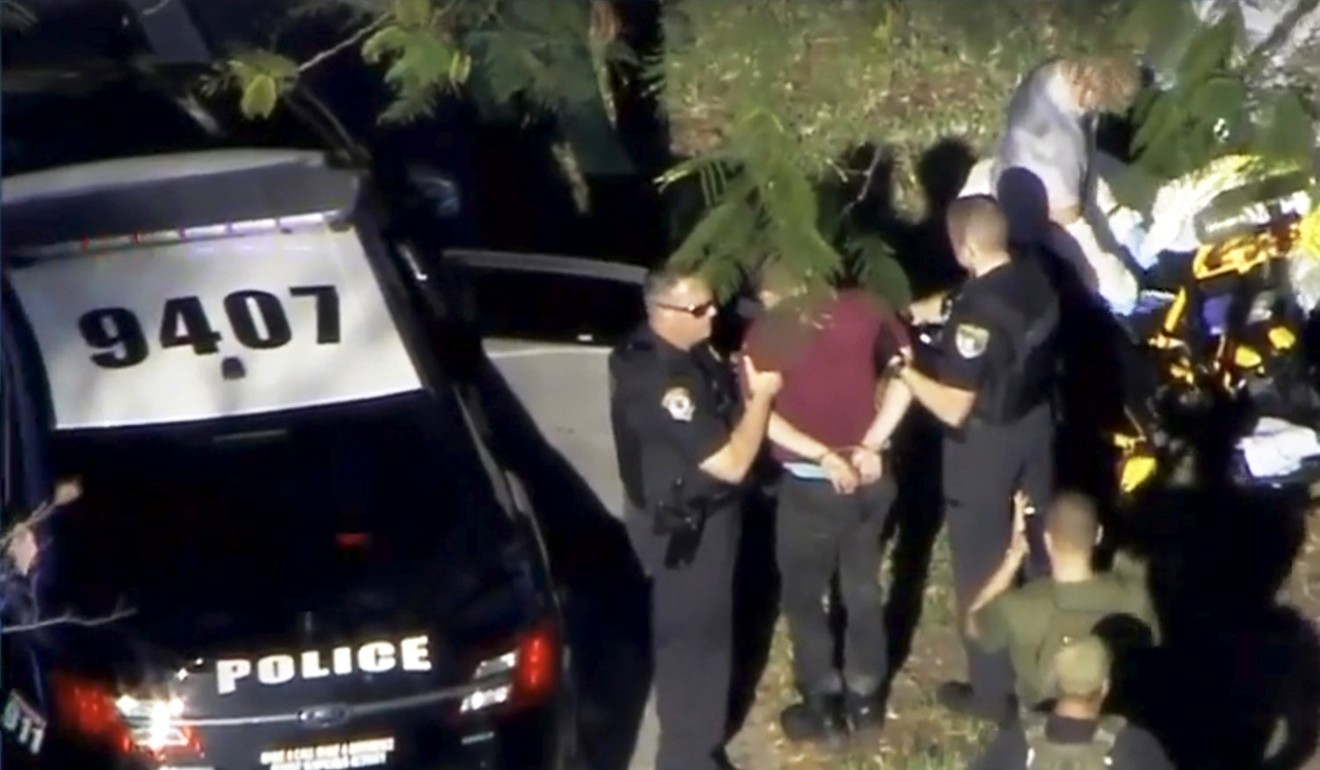 A man placed in handcuffs is led by police near Marjory Stoneman Douglas High School following a shooting incident in Parkland, Florida. Photo: Reuters
