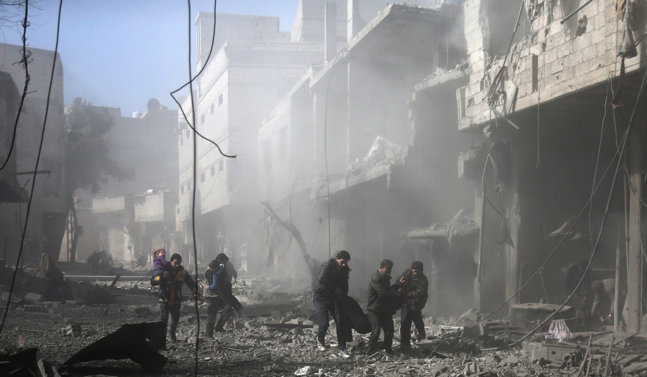 Syrian men carry an injured victim amid the rubble of buildings following government bombing in the rebel-held town of Hamouria, in the besieged Eastern Ghouta region on Monday. Photo: Agence France-Presse