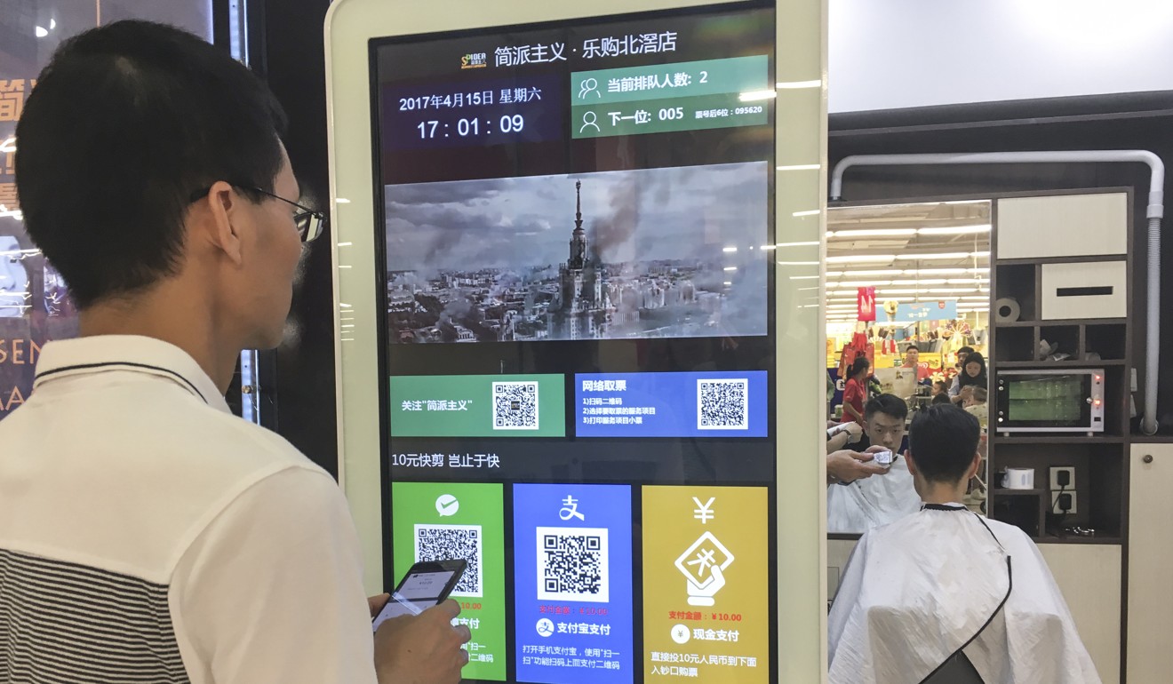 A man considering his payment options outside a barber shop in Guangzhou, Guangdong province. Photo: Martin Chan