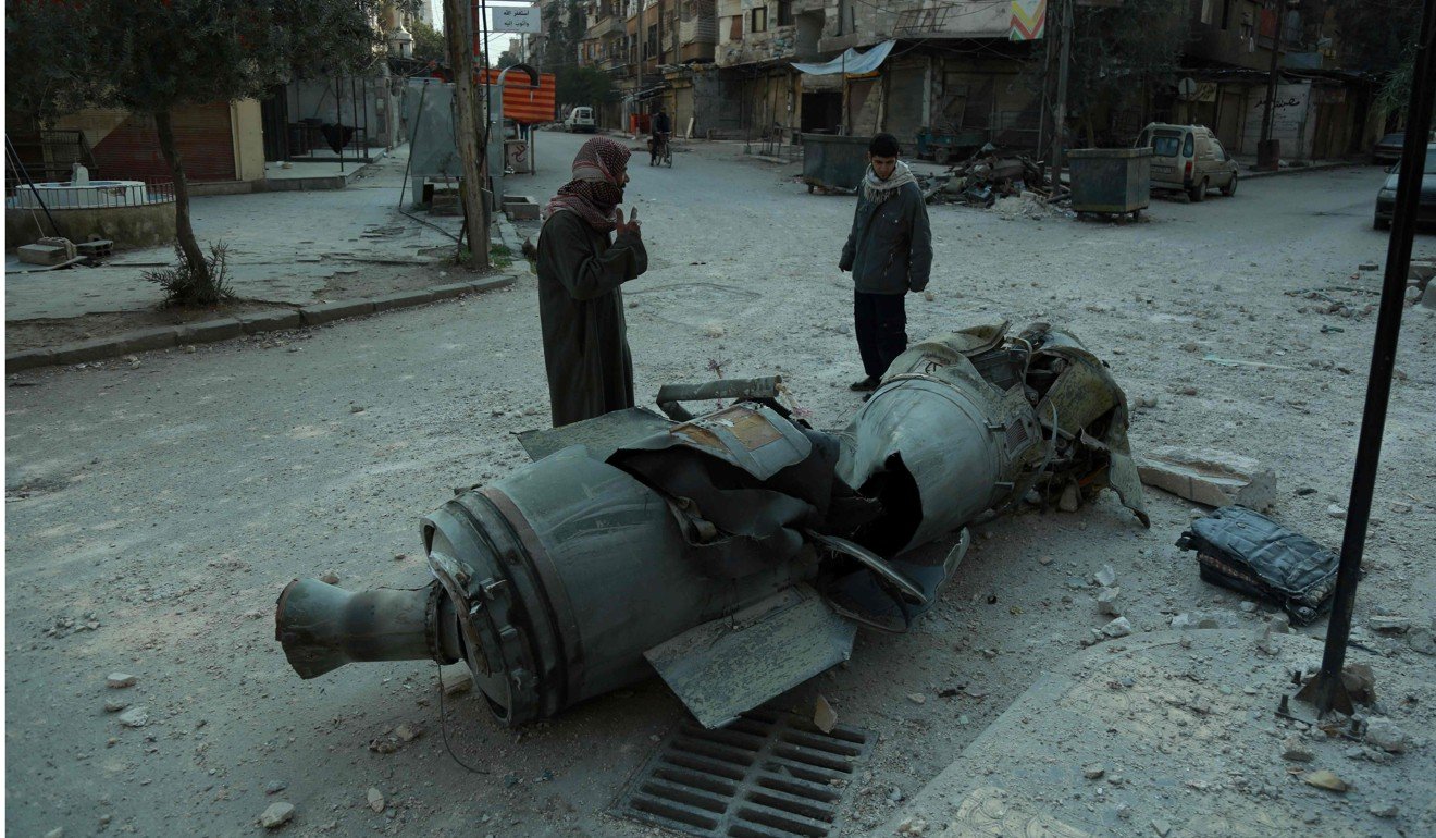 Men walk past the remains of a rocket in the rebel-held town of Douma. Photo: AFP