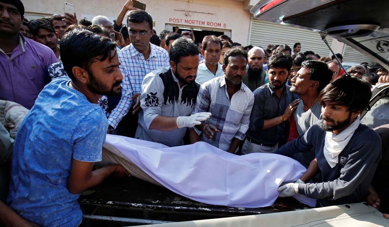 People move the body of a victim, who died in an accident after a truck carrying wedding party guests plunged into a dry riverbed. Photo: Reuters