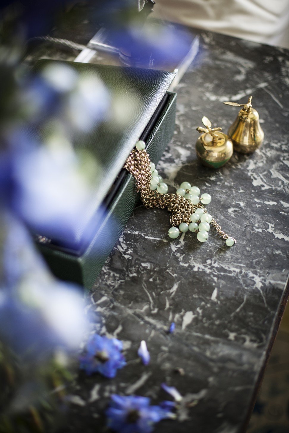 The sapphire blue jewellery box stands out against the marble top of the bedside cabinet.