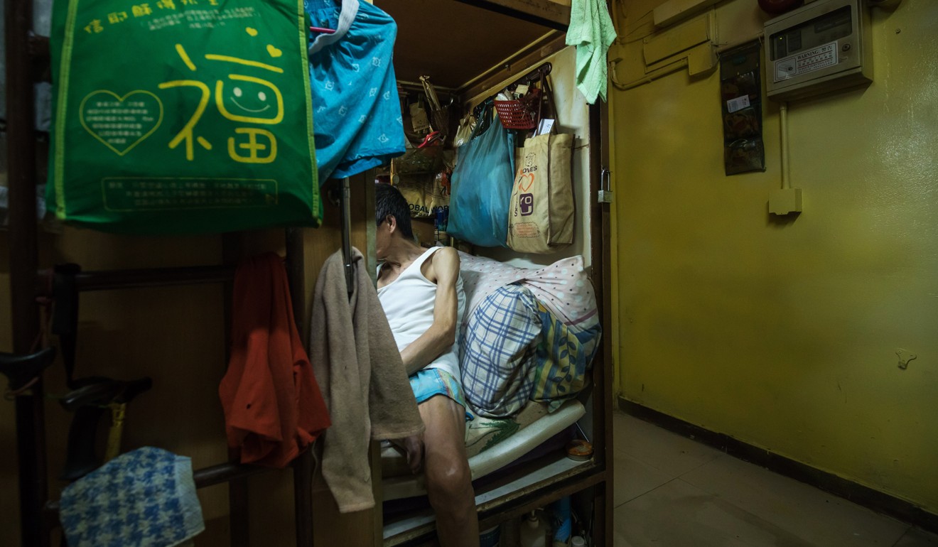 A man sits inside a subdivided residential unit, known as a “coffin home”, in Hong Kong. Research on life in subdivided flats found that many occupants suffered mental stress from the poor conditions. Photo: Bloomberg