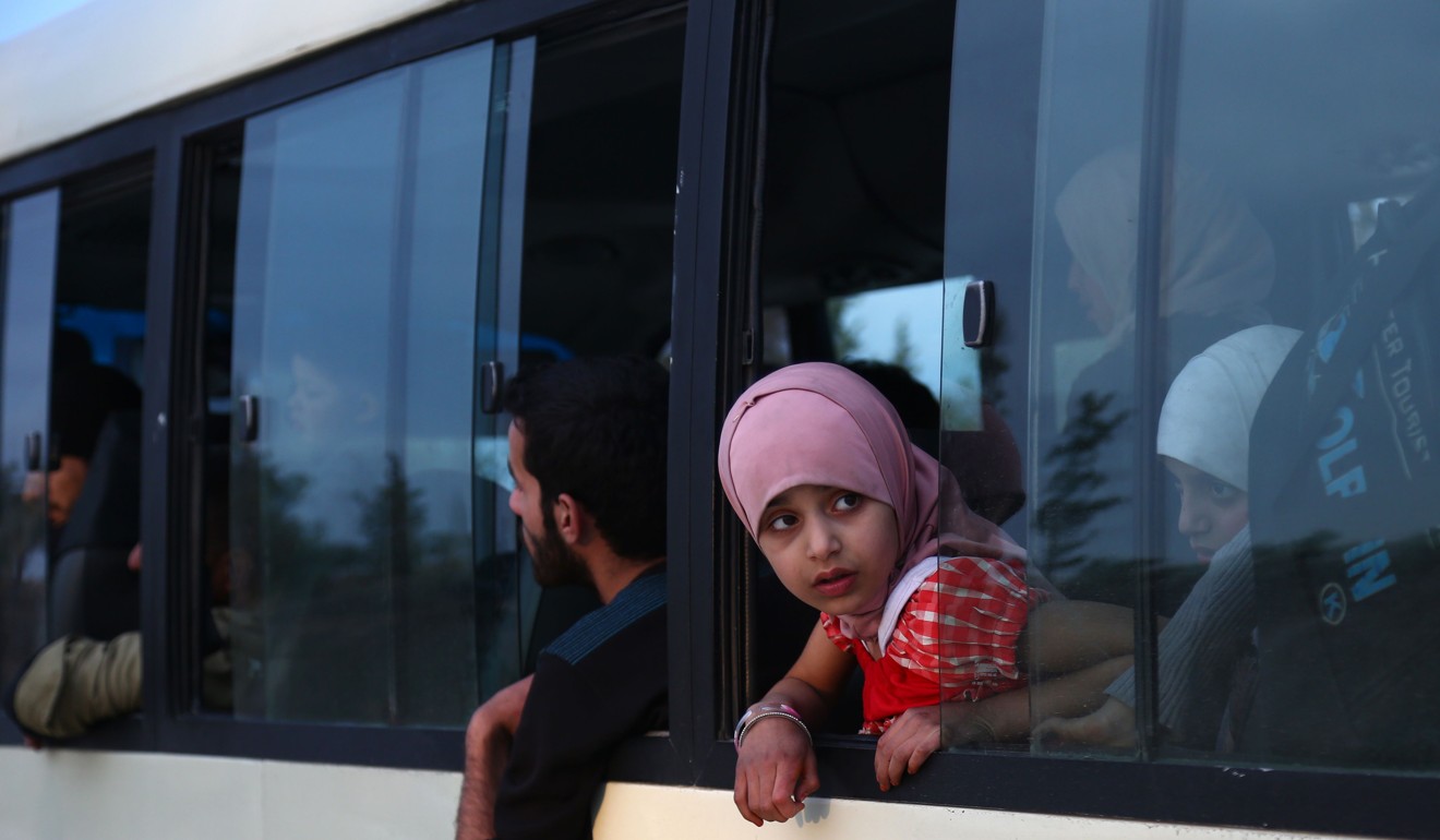 A girl looks out from a bus carrying Jaish al-Islam fighters and their families from their former rebel bastion of Douma on Thurday as it arrives at the Abu al-Zindeen checkpoint controlled by Turkish-backed rebel fighters near the northern Syrian town of al-Bab. Photo: AFP 