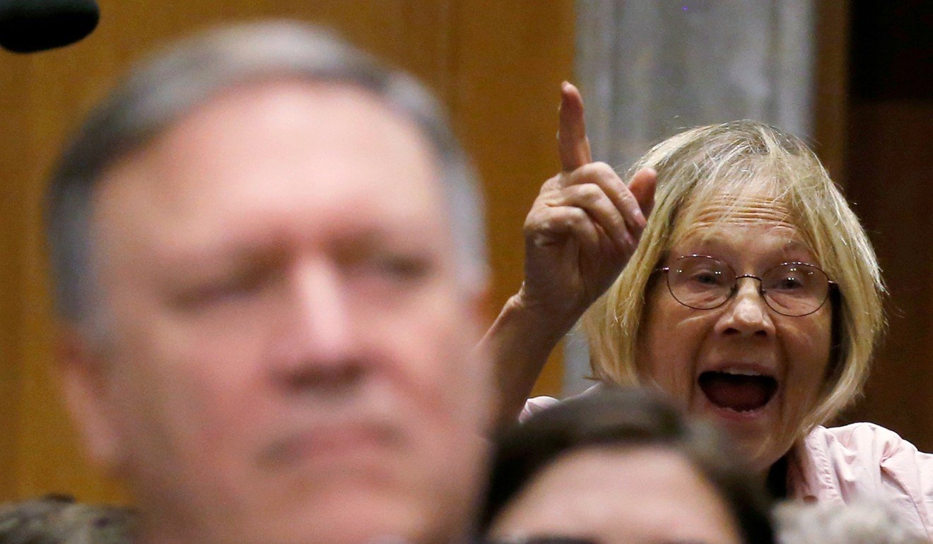 A protester from Code Pink is escorted out of the room as she yells at Pompeo before his testimony. Photo: Reuters