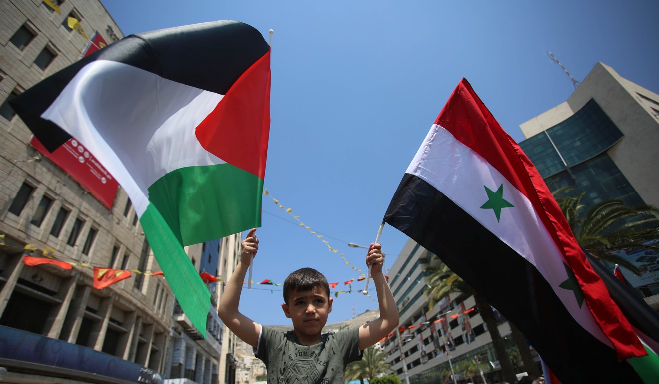 A Palestinian boy in the West Bank waves Syrian and Palestinian flags during a protest against the US following a wave of military strikes on Syria. Photo: Xinhua