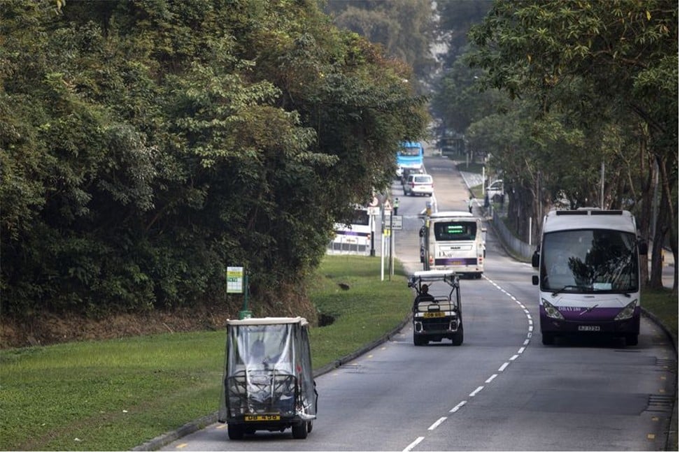 Golf carts and commuter buses travel along a two-lane road. Photo: Justin Chin/Bloomberg