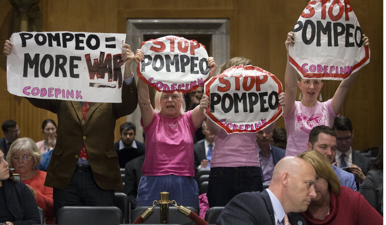 Protesters hold signs behind White House Legislative Affairs Director Marc Short (front) before the Senate Foreign Relations Committee meeting on Monday to consider the nomination of CIA Director Mike Pompeo to be Secretary of State. Photo: EPA