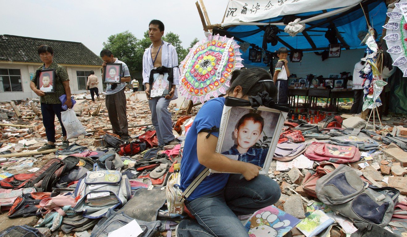 Parents hold pictures of their children outside a primary school in Wufu township in Sichuan province. More than 200 of the school’s 300 or so children were killed or injured in the earthquake, according to villagers. Photo: Robert Ng