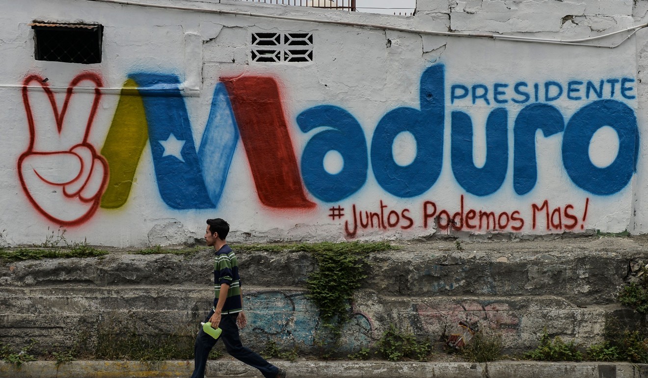 A man walks past a graffiti in support of Maduro. Photo: AFP