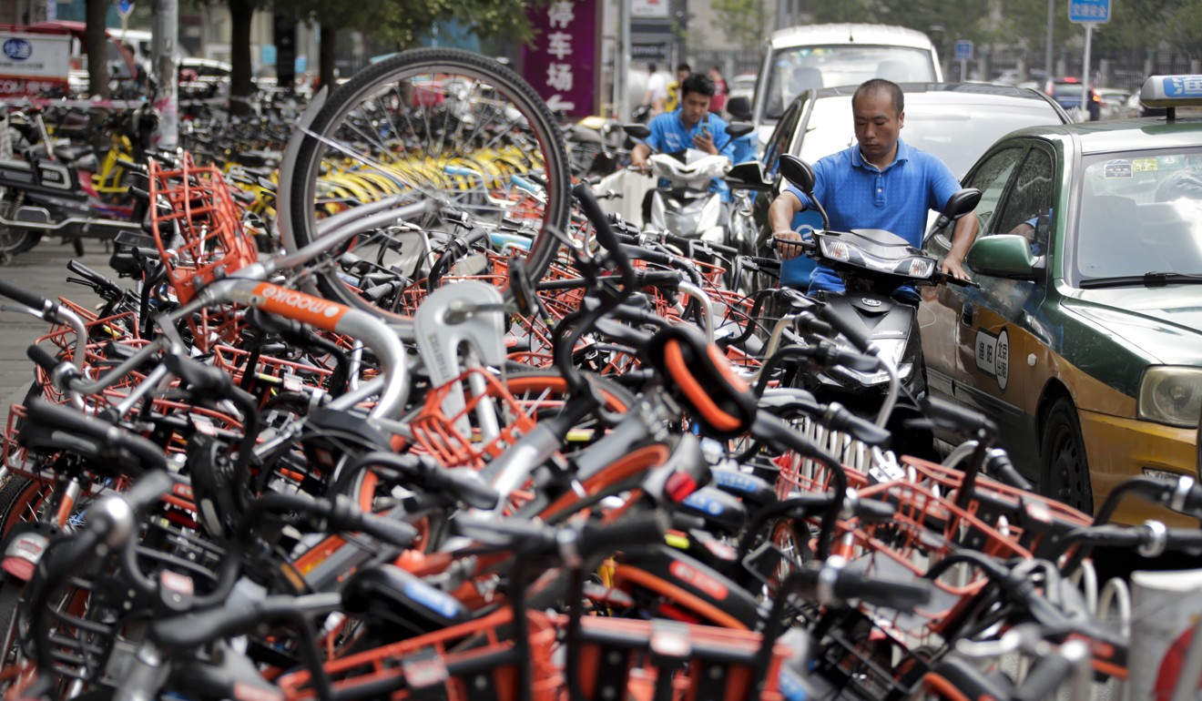 A man on his electric motorbike scooter tries to pass a busy traffic car lane as a stack of shared bicycles block the cycle lane on a street in Beijing. Photo: AP