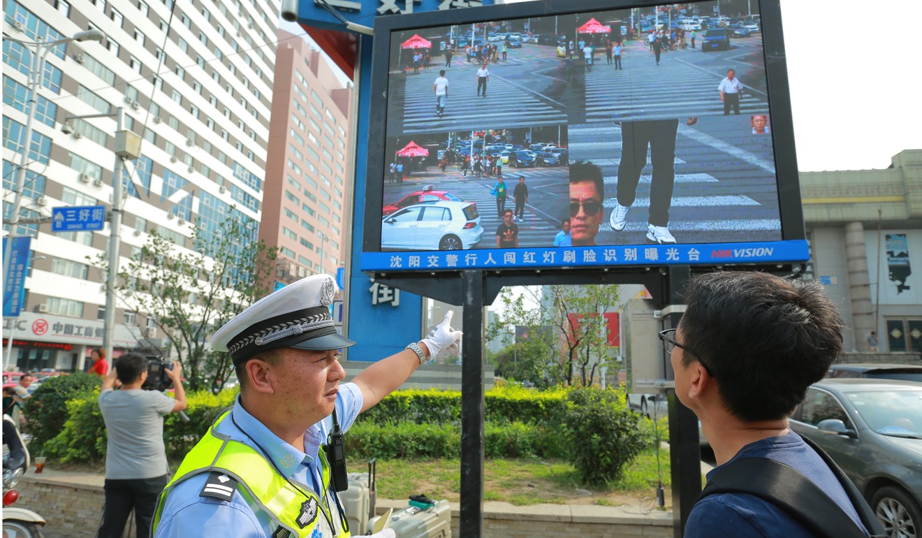 A traffic policeman shows a man that he has been facially identified while jaywalking in Shenyang city in northeast China's Liaoning province in September last year. Photo: China Foto Press