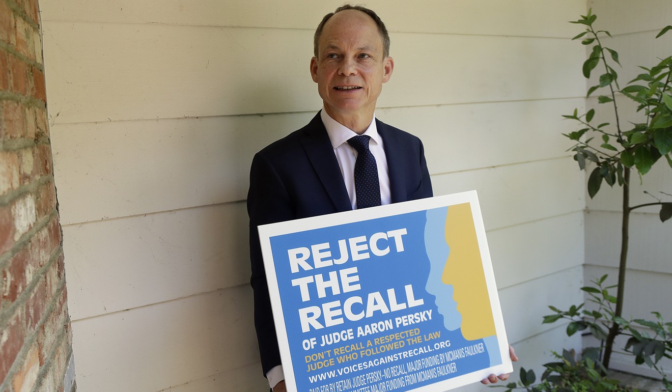 Judge Aaron Persky poses for a photo with a sign opposing his recall in Los Altos Hills, California in May. Photo: AP