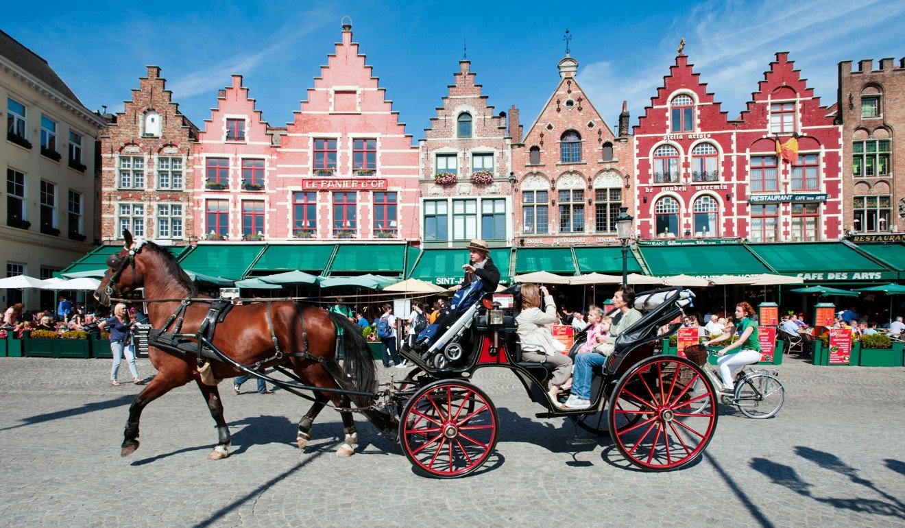 Tourists enjoying a tour of Bruges in Belgium on a horse-drawn carriage. Picture: Alamy