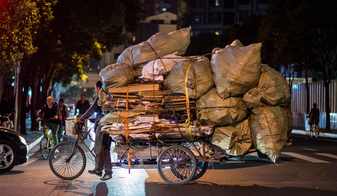 This picture taken on May 11 shows a scrap collector steering his tricycle loaded with plastic and paper waste through the streets of Shanghai. Photo: AFP