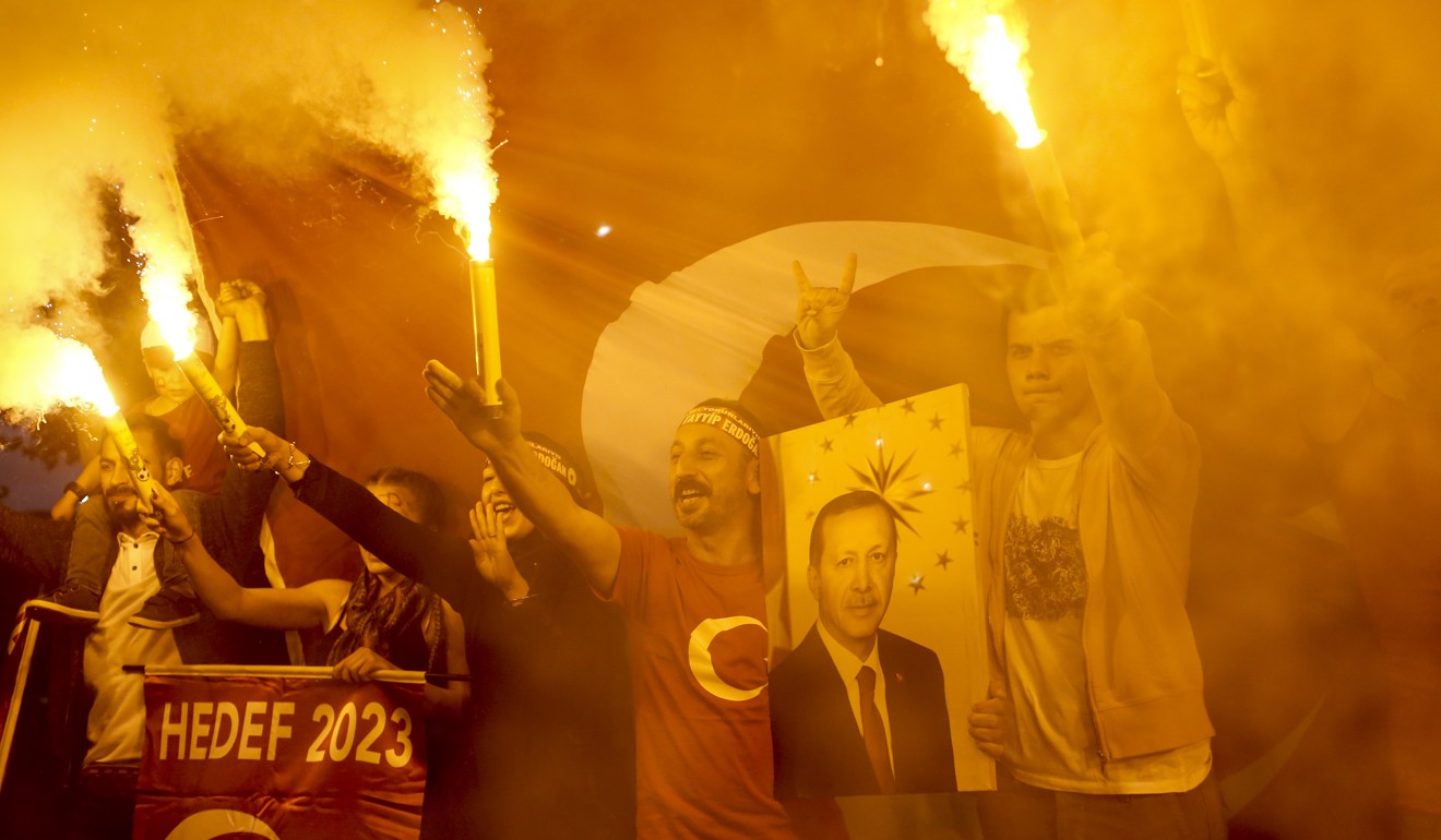 People hold flares and an image of Recep Tayyip Erdogan, Turkey's president, outside the AKP party headquarters as they react to the outcome of the parliamentary and presidential elections in Istanbul. Photo: Bloomberg