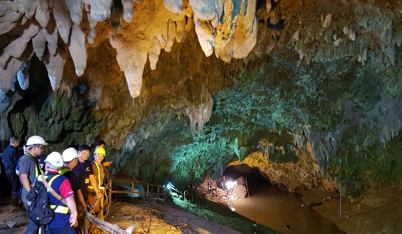 Thai workers and associated officials look into the flooded cave as they attempt to drain the water. Photo: EPA