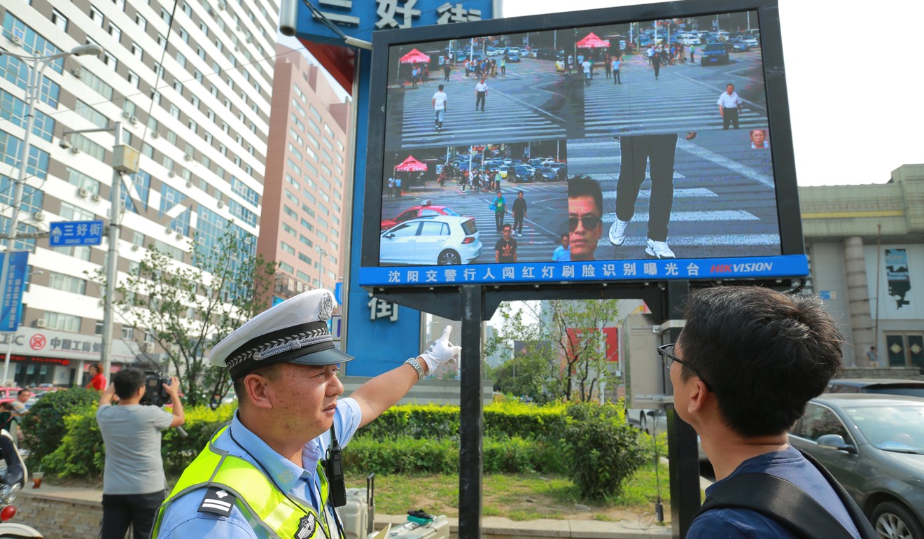 A traffic policeman shows a man that he has been identified, through facial recognition, while jaywalking at a street in Shenyang city, located in northeast China's Liaoning province. Photo: China Foto Press