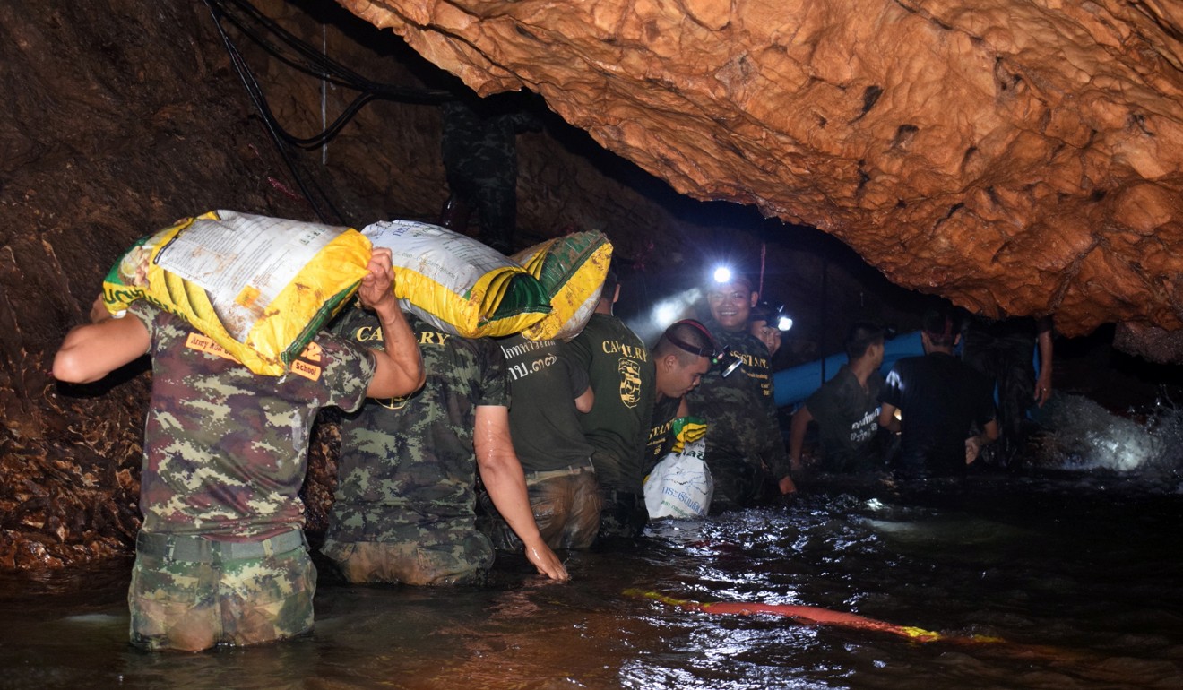 Thai soldiers carry supplies and equipment into the flooded cave where a group of 12 young soccer players and their coach have been trapped for days. Photo: EPA