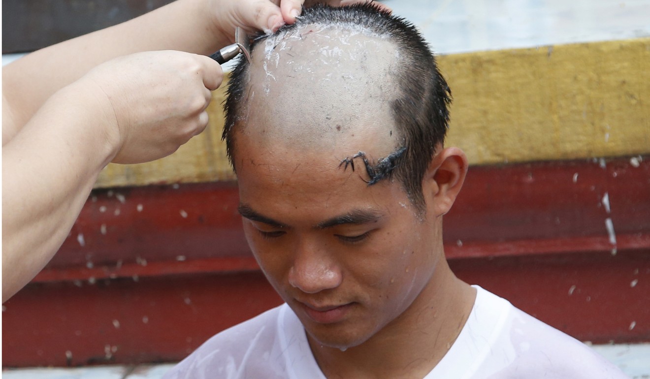 Soccer coach Ekkapol Chantawong getting his head shaved. Photo: AP