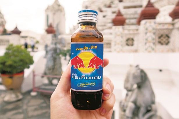 A bottle of Krating Daeng showing two red wild gaur about to butt heads in front of a yellow sun. Photo: Shutterstock