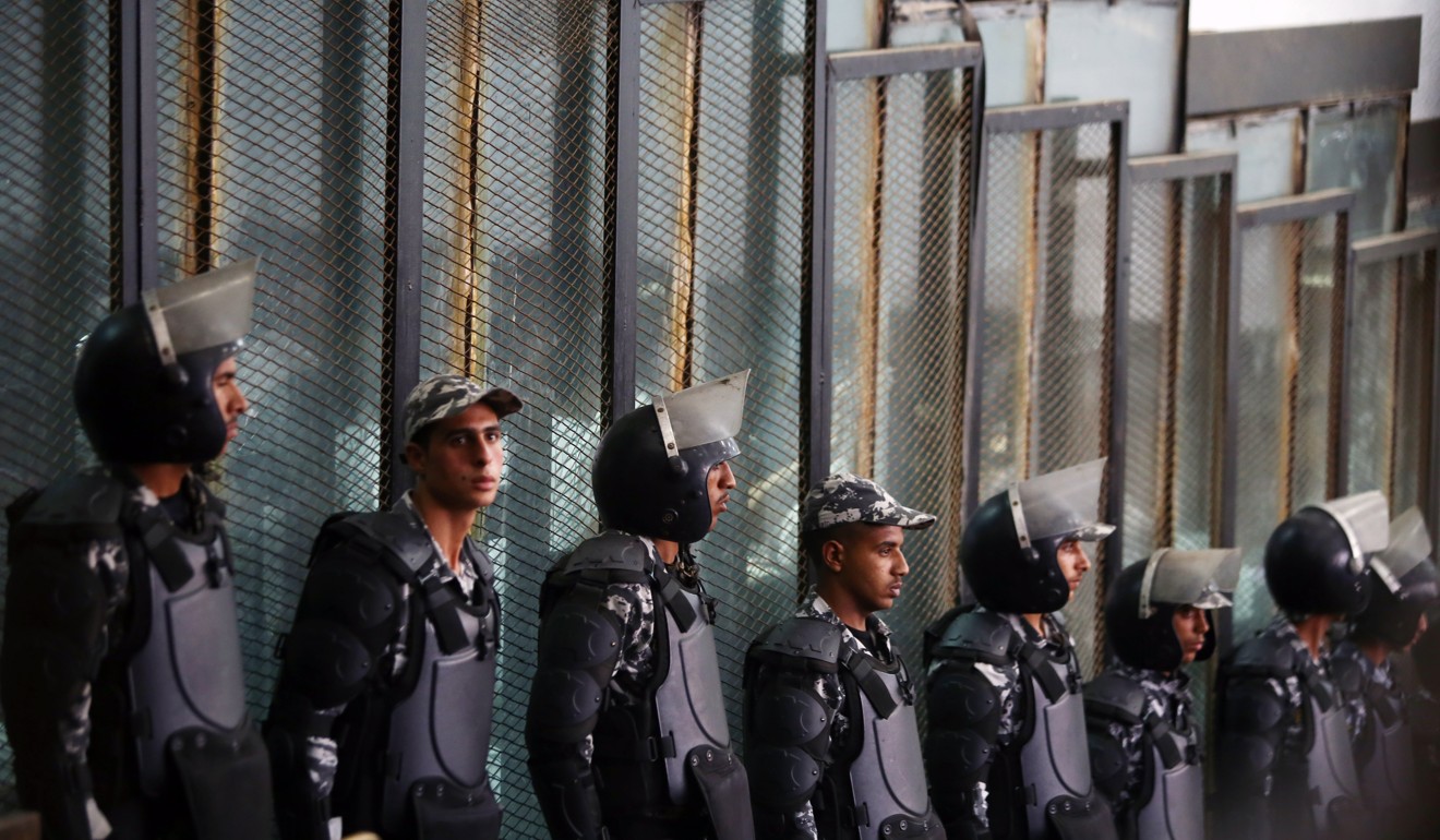Police officers standing guard over suspects behind a fence in a Cairo court. Photo: Xinhua