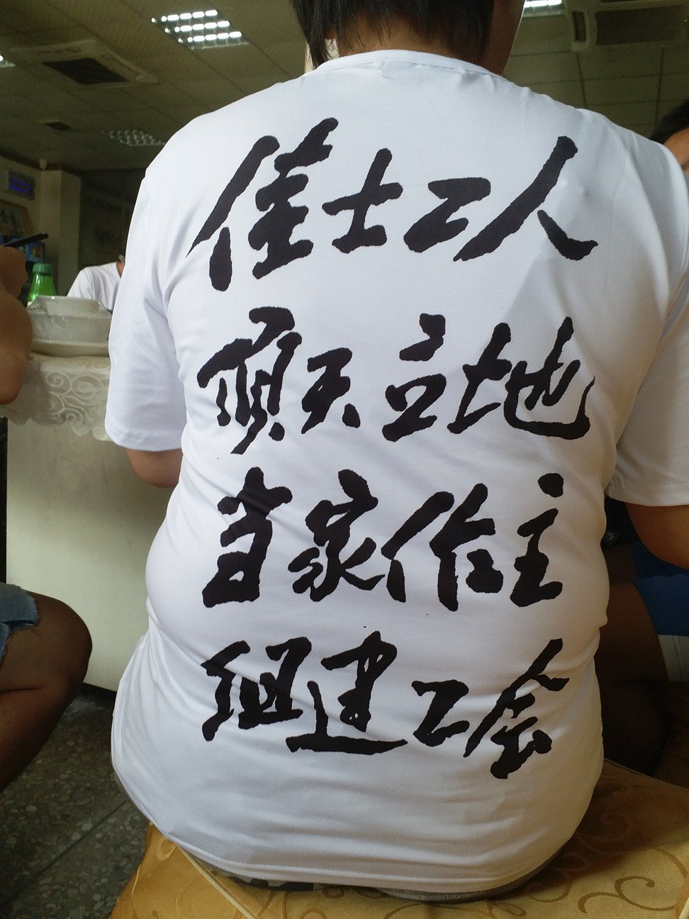 Slogans on the back of a protester’s T-shirt urge Jasic workers to stand “upright” and be their own boss. Photo: Mimi Lau.