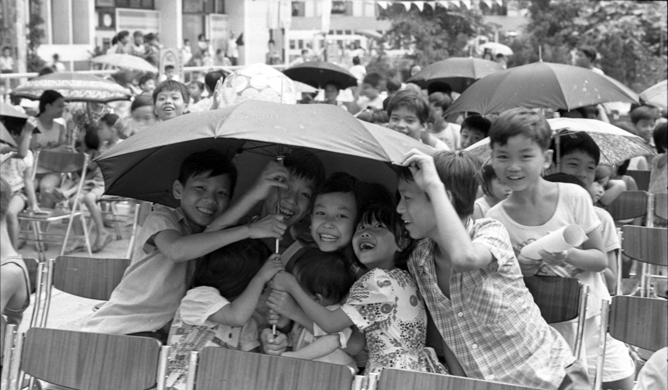 Children giggle while sharing an umbrella at a fun fair in Kwai Fong Estate in July 1977. Small acts of kindness can go a long way. Photo: Sunny Lee