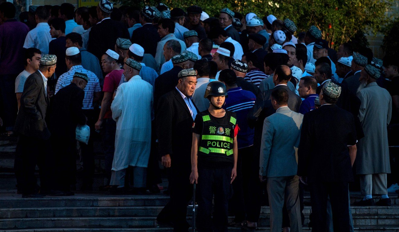 A police officer stands guard as Muslims arrive for morning prayer during Eid al-Fitr at the Id Kah Mosque in Kashgar, in China’s Xinjiang Uygur autonomous region. Photo: AFP