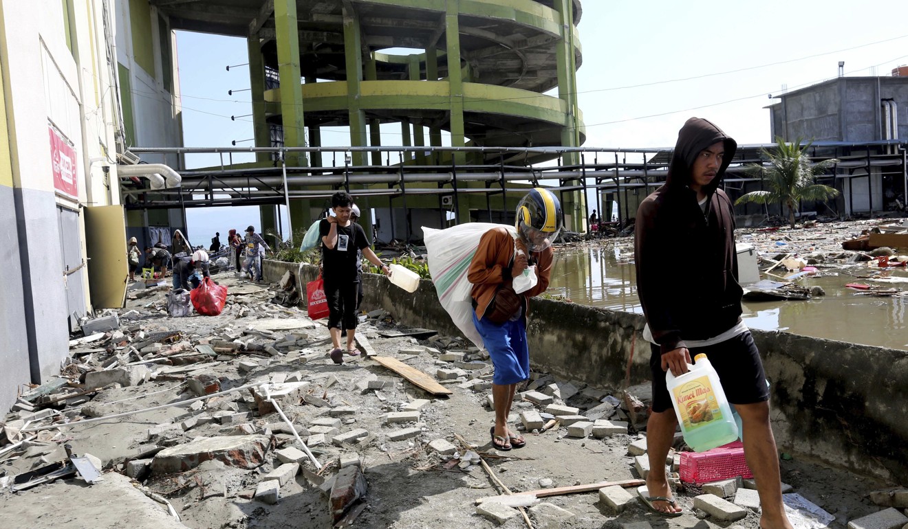 People walk away with items from the damaged shopping centre. Photo: AP