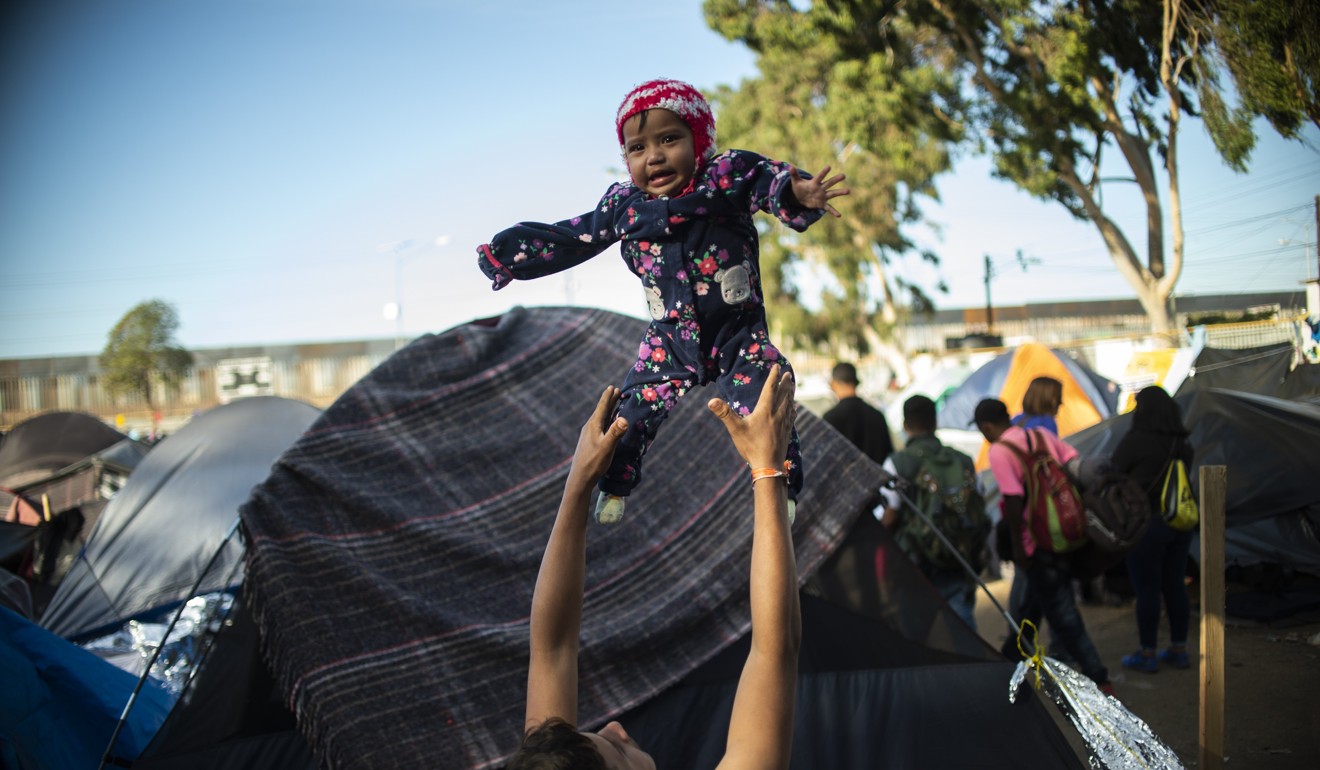 A Central American migrant wanting to reach the US plays with a child at a shelter in Tijuana. Photo: AFP