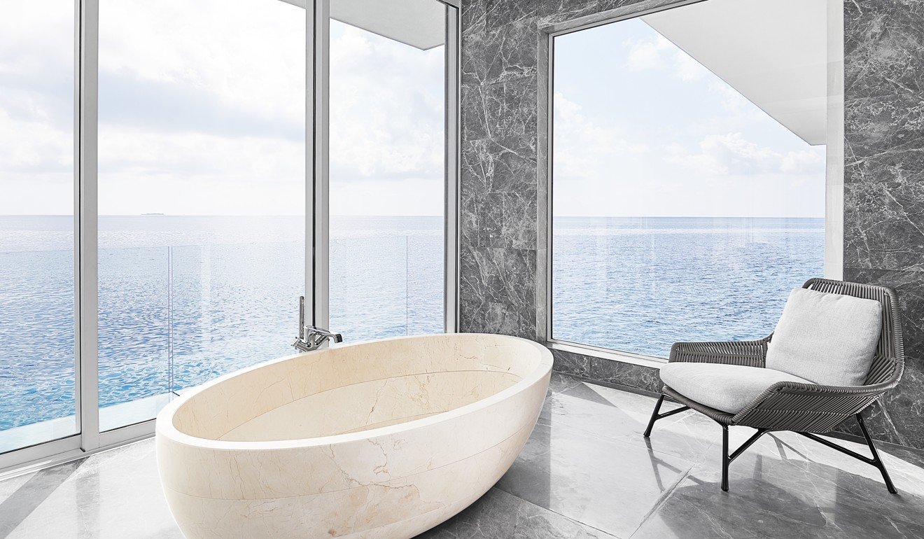 A marble bathtub sits in the corner of the bathroom beyond the bedroom, with clear views of the deep blue waters. Photo: Justin Nicholas