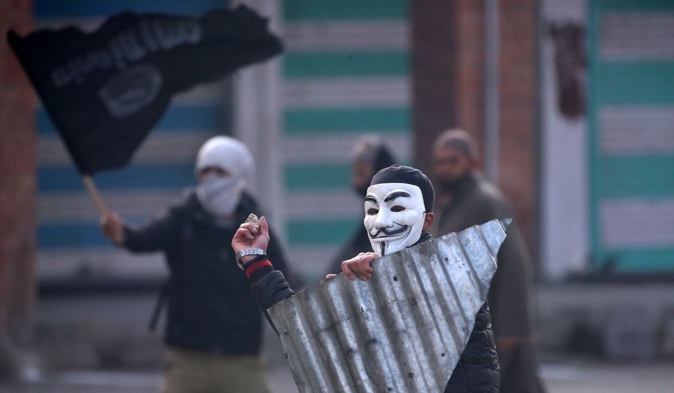 A demonstrator wearing a Guy Fawkes mask throws a stone towards Indian police (not pictured) during a protest after Friday prayers, in Srinagar. Photo: Reuters