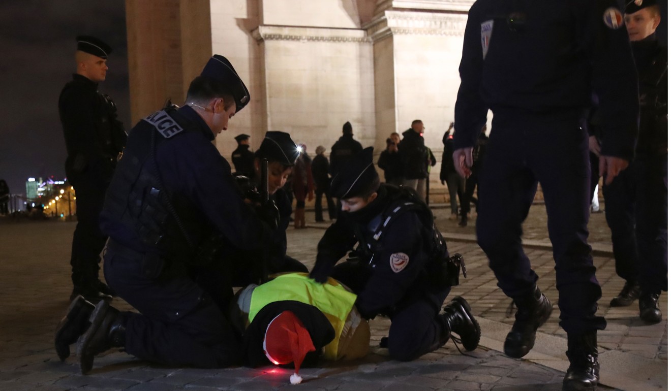 A yellow vest anti-government protester wearing a Father Christmas hat is arrested by French police at the Arc de Triumph in central Paris on December 24, 2018. Photo: AFP