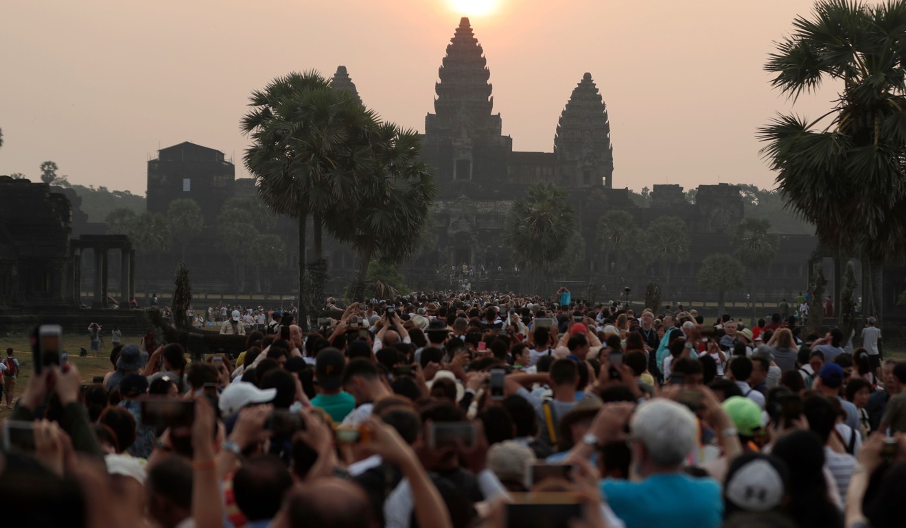 The sun rises over the central stupa of Angkor Wat temple in Siem Reap as hoards of tourists take photos. Photo: AFP