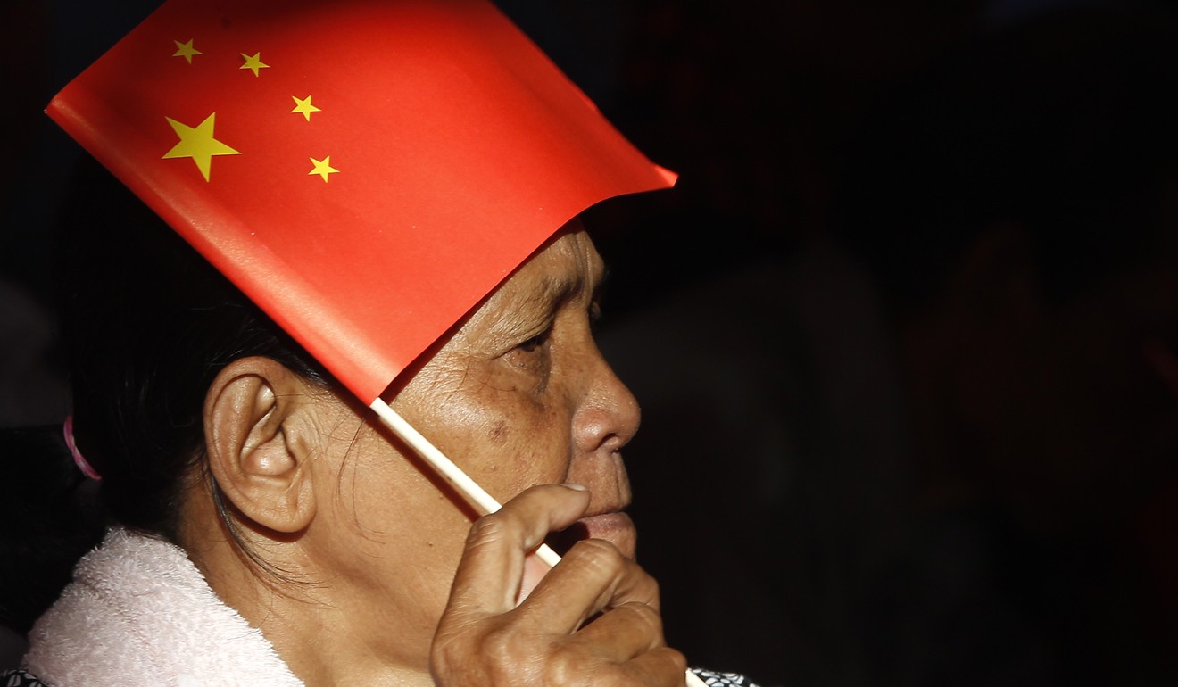 A woman uses a Chinese national flag to protect herself from the sun as she listens to Prime Minister Hun Sen deliver a speech about a sky bridge funded by China. Photo: AP