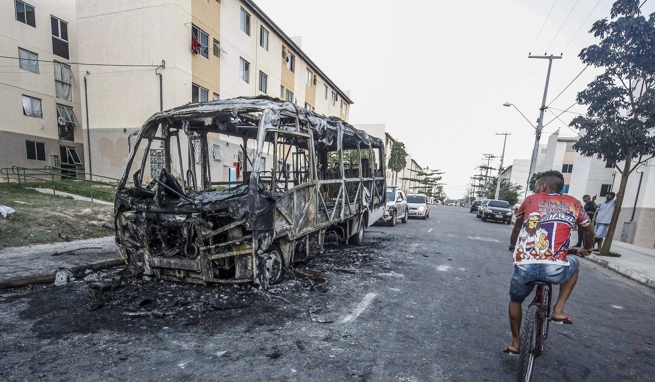 A man riding a bicycle in front of a bus burned during a vandalic attack in Fortaleza, Ceara state, northern Brazil, 04 January 2019. Photo: EPA-EFE/Jarbas Oliveira