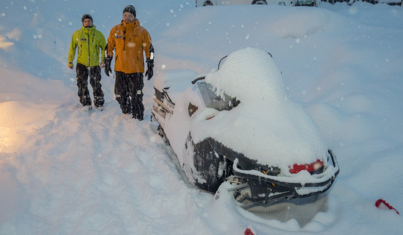 Volountary rescuers near a snow scooter in Tamokdalen, Norway, where the search for four missing skiers has been suspended due to bad weather. Photo: EPA