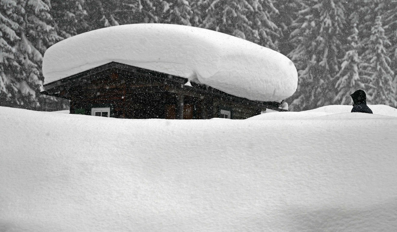 A person walking by a snow-covered hut on Tuesday in Ramsau am Dachstein, Austria. Photo: AFP