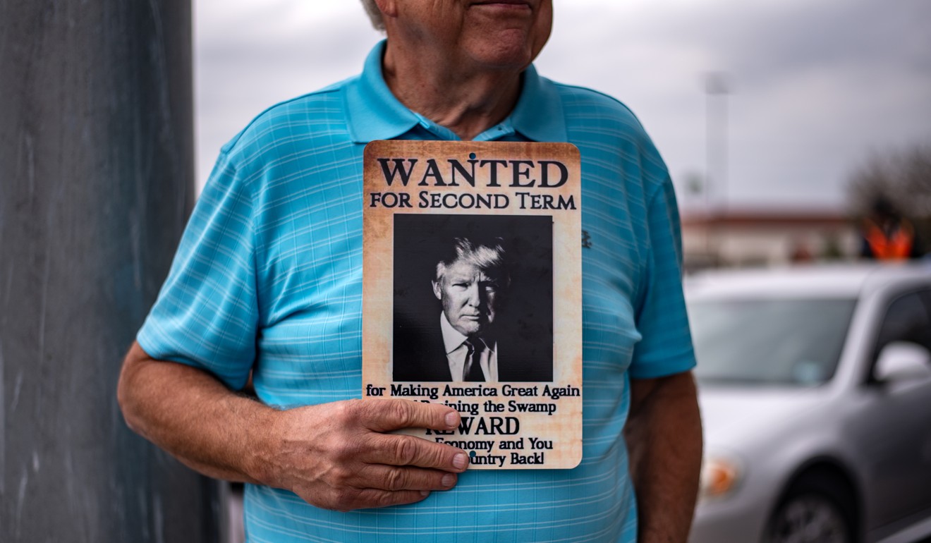 A man holds a “Wanted For Second Term” sign with an image of Donald Trump, at a gathering near McAllen-Miller International Airport in Mcallen, Texas on Thursday. Photo: Bloomberg