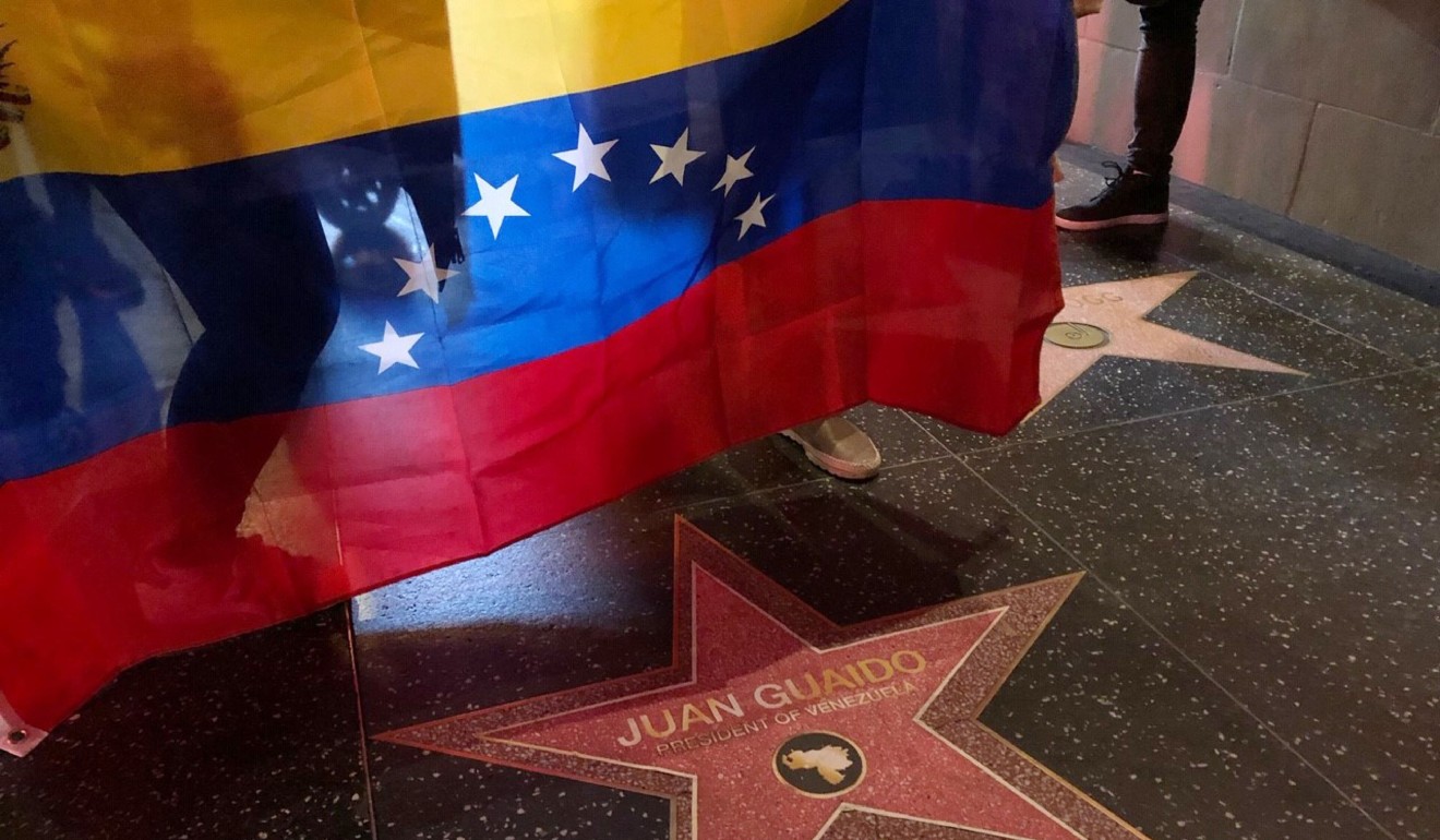 People hold a Venezuelan flag near a paper star reading “Juan Guaido President of Venezuela” placed on the Hollywood Walk of Fame during a demonstration held by Venezuelans in support of Guaido in Hollywood on January 23, 2019. Photo: AFP
