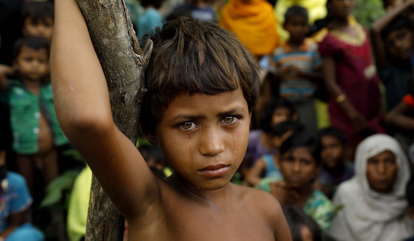 A Rohingya refugee girl next to newly arrived refugees who fled to Bangladesh from Myanmar. Photo: AFP